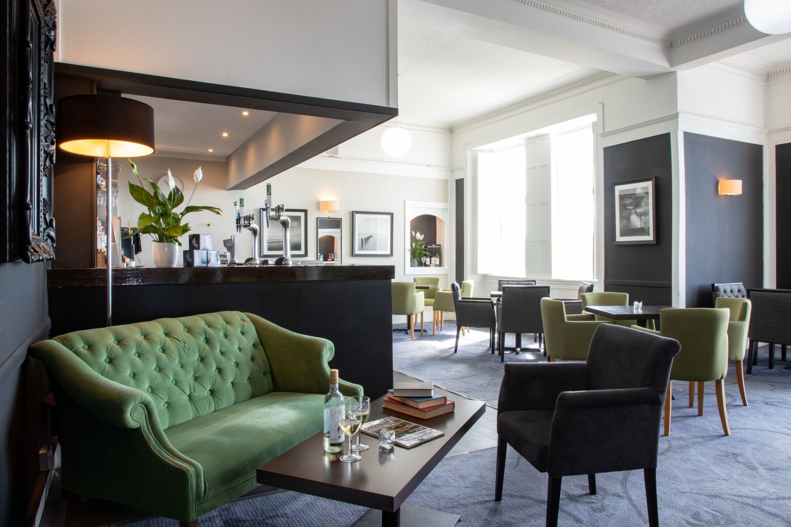 a room with a green couch and black chairs